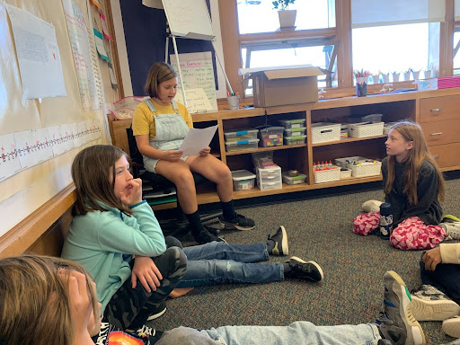 A student reads her finished essay aloud to the class at the end of a Being a Writer unit.