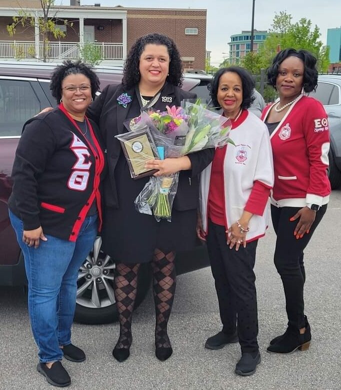Barbara Patterson Oden, Learning Leader and Manager of Educational Partnerships in the District of Columbia and Virginia, is shown holding flowers and an award, surrounded by her soroity sisters.
