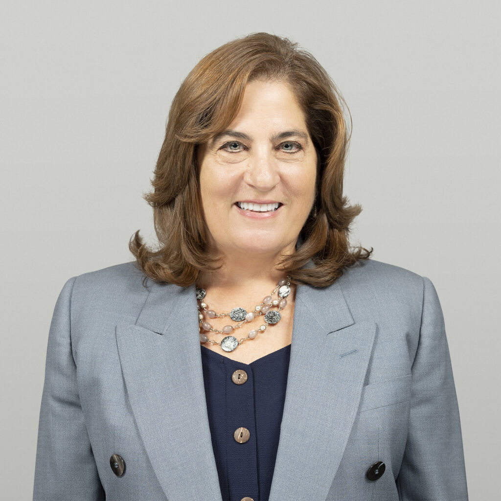 Headshot of Stacy Storm, Manager of Educational Partnerships at Collaborative Classroom. Stacy has red, shoulder-length hair and. is wearing a gray suit jacket over a dark blue shirt accessorized by a large 3-tiered necklace.