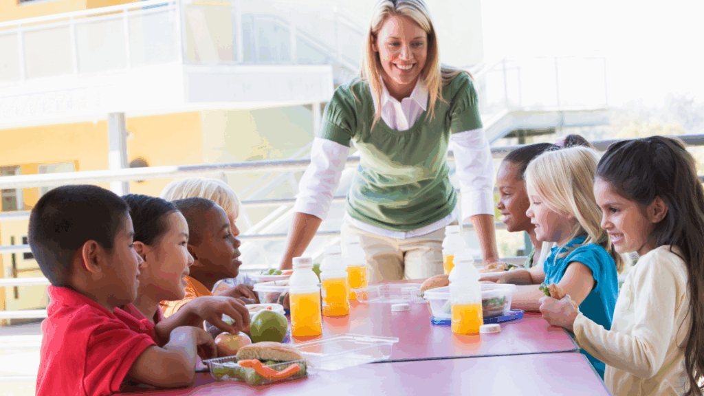Preschool teacher in early childhood environment using oral language and vocabulary strategies during meal time.