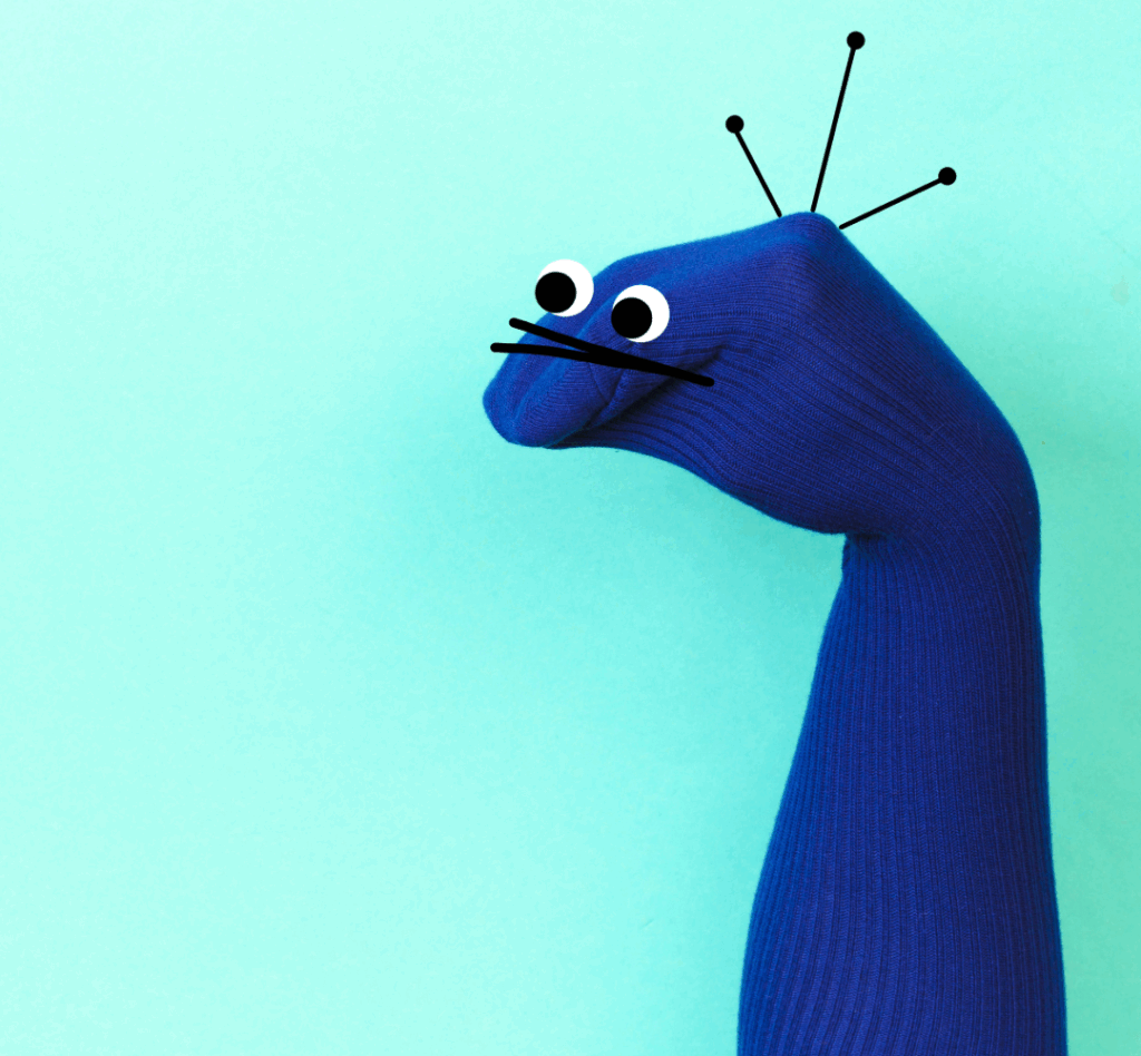 Photo shows a dark blue sock puppet with antenna and googly eyes.