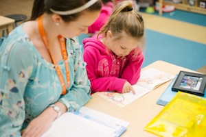 teacher listening to student read trade book