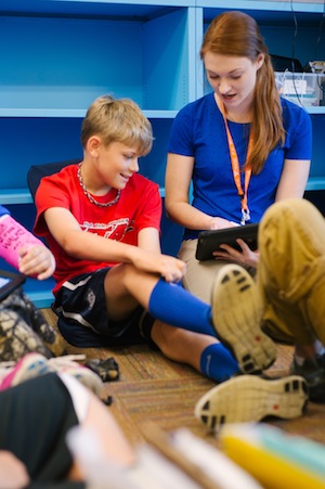 student and teacher looking at a tablet computer