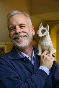 photo of Chris Van Allsburg with a replica of his canine character Fritz sitting on his shoulder